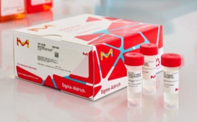 p9080 A white and red laboratory reagent box is placed on a clean surface alongside three small clear sample vials with red caps.