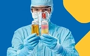 一名身着个人防护装备（PPE）的人正手持两支试管，一支装有黄色液体，另一支装有粉色液体。背景为鲜艳的蓝色，上面有一道黄色的抽象图案，与人物和试管形成了鲜明的对比。