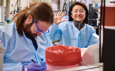 A smiling scientist working together with colleagues in a laboratory setting. A smiling scientist working together with colleagues in a laboratory setting.