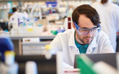 Scientist working on a laptop in a laboratory setting Scientist working on a laptop in a laboratory setting