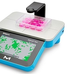 Photograph of the Millicell® DCI Digital cell imager for measuring confluency and cell count, with plate of hanging cell culture inserts in 24-well format on platform