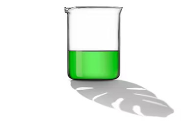 Eco Detergents and Greener Surfactants Glass beaker containing bright green liquid, casting a shadow on a white surface.