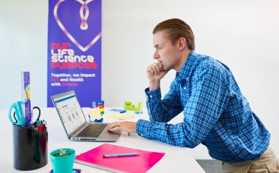 Scientist sitting at a desk, looking at a computer with data. Scientist sitting at a desk, looking at a computer with data.
