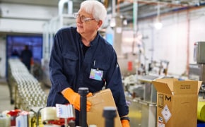 Operator Packing Products A photo featuring an operator packing products in a factory next to a production line.