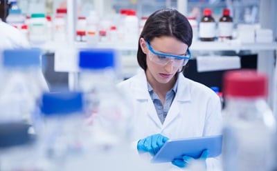 Analytic Chemistry Chemist wearing safety glasses and using tablet pc in lab testing for Coronavirus Covid19 vaccine.