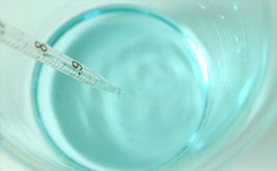 一台温度计正在测量玻璃容器中透明蓝色液体的温度。