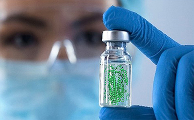 Scientist holding a vial containing green glycoconjugate beads, representing biomolecule conjugates for life science and biomedical research.