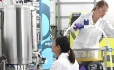 Bioprocessing cell culture media (CCM) Two scientists work to the right of a bioreactor