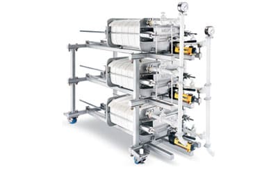 An industrial clarification filter system featuring multiple cylindrical units mounted on a metal frame, complete with gauges and valves, designed for large-scale filtration processes.