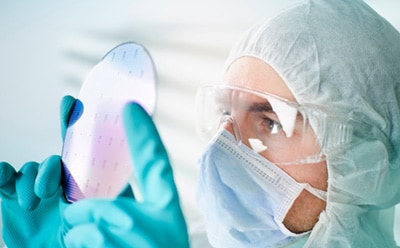 Prefabricated pre-patterned electronic device substrate Scientist wearing protective clothing inspecting prefabricated pre-patterned electronic device substrate
