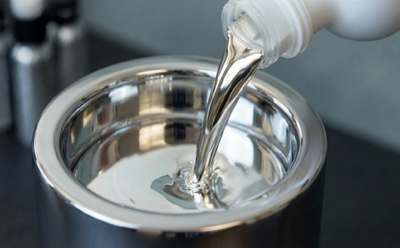 Liquid Alloy Pouring 一个表面具有反射效果的金属容器,正从一个白色瓶子中注入一种透明、闪亮的液态合金。该图像由人工智能生成。