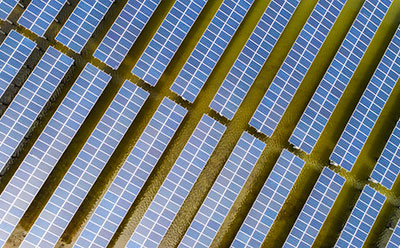 Top-down view of a floating photovoltaic array consisting of modular solar panels arranged in parallel rows on a water body, illustrating large-scale renewable energy deployment.