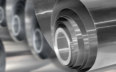 Several rolls of aluminum metal material, showcasing their smooth, reflective surfaces.