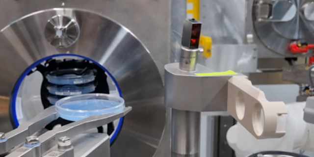<p>Automated Environmental Monitoring in Gloveless Isolators</p>
Automated equipment transfers a culture plate inside a stainless-steel isolator.