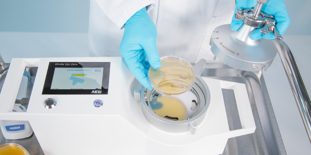 <p>Microbial sampling of compressed gases</p>
Blue-gloved worker places a culture plate into a compressed-gas microbial sampling device.