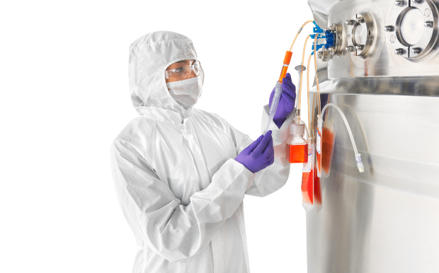 An individual in full-body white protective gear, operating in a biopharmaceutical manufacturing environment, is taking samples from biopharmaceutical equipment using NovaSeptum® sampling solutions. 