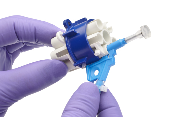 White plastic holder with blue plastic band and connection  points for NovaSeptum® GO sampling system. Plastic security tag prevents accidental actuation.