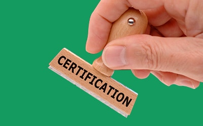 The image depicts a hand poised to stamp with a wooden rubber stamp labeled “CERTIFICATION” against a vibrant green backdrop.