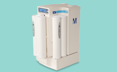 Compact AFS 24 water purification system with two cylindrical filtration cartridges on the front, a small digital display screen showing '5.0 °C', and a large blue 'M' on the side, all set against a light turquoise background 