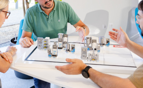 Consider options for designing flexible manufacturing A team reviewing a tabletop process and equipment layout model to evaluate flexible design options for a biopharmaceutical manufacturing facility. Represents Millipore's support for future-ready plant design.