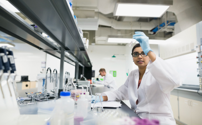 Bacterial retention Scientist in a laboratory raises a pipette while working among bottles and other lab equipment.