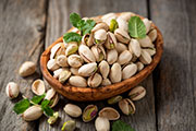 Bowl with pistachios on a wooden table. A bowl of pistachios.