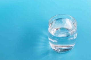 Drinking water 蓝色背景上有一玻璃杯饮用水