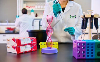 PURedit<sup>®</sup> Cytosine Base Editor Kits In The Lab Female scientist pipetting at the bench with male scientist in background. On the bench is a DNA molecule, colorful tube racks, pipettes, and the PURedit® cytosine base editor kit.