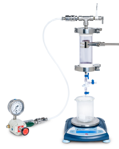 Pressure gauge is shown on left connected by tubing to the pressure vessel which is filled with product and has metal clamps to secure in place above the small-scale filter (white). Blue valves allow venting of the system 