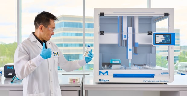 Scientist with PureProteome™ Magnetic Beads for AAW™ Workstation 科学家站在带有 PureProteome™ 台架的 AAW™ 自动测试工作站前竖起大拇指。