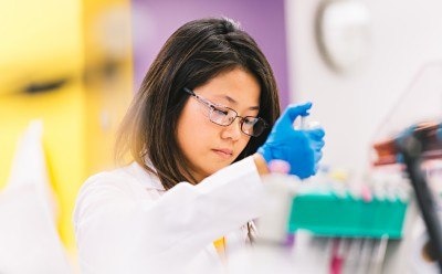 Lab worker pipetting at a work station.