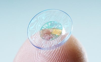 Contact lens with sensor in middle held on fingertip.