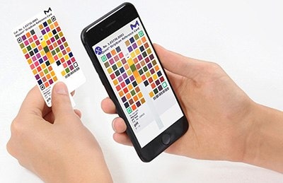 A person's hands holding a color chart card in one hand and a smartphone in the other. The smartphone screen displays a digital version of the same color chart, aligning the physical and digital formats for comparison or analysis. The background is white, emphasizing the items being held. A person's hands holding a color chart card in one hand and a smartphone in the other. The smartphone screen displays a digital version of the same color chart, aligning the physical and digital formats for comparison or analysis. The background is white, emphasizing the items being held.