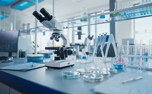 A modern laboratory setting with a microscope in the foreground and various scientific equipment like test tubes, beakers, and flasks in the background.