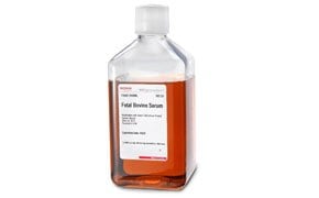 The image displays a clear plastic bottle with a white cap, filled with a red liquid identified as “Fetal Bovine Serum.”