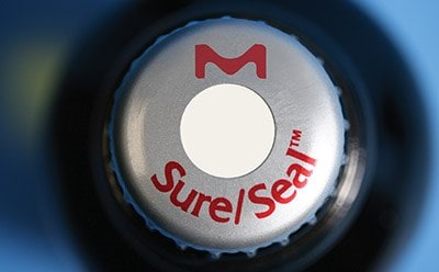 Organolithium products with Sure/SealTM Packaging Close-up of a bottle cap featuring a logo with an ‘M’ above a white circle, and the text “Sure|Seal™” in red around the lower edge of the circle.