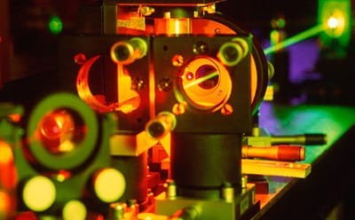 Image of optical components guiding laser pathway through hole in machinery in factory