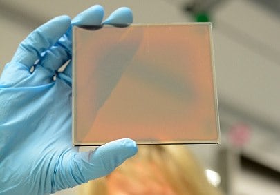 A scientist holding thin-film solar cell inspects quality