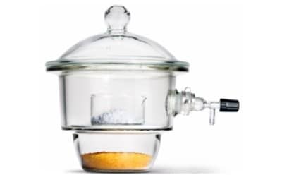 圆形玻璃容器，盖子密封，顶部有旋钮，便于操作。干燥器内部有两个腔室：上腔室放置一个透明的小碟子，里面装有白色或灰色物质，可能是样品。下腔装有一种橙色的颗粒状物质--干燥剂，它可以吸收水分。干燥器配有一个用于连接真空的侧阀，可以排出空气，创造一个低湿环境。整个设备由透明玻璃制成，外观时尚。