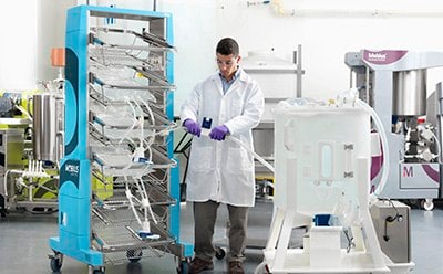 Connecting a 2D bag assembly for mixing 实验室技术人员在将Mobius®容器推车上的2D袋组件连接到Mobius®混合仪上