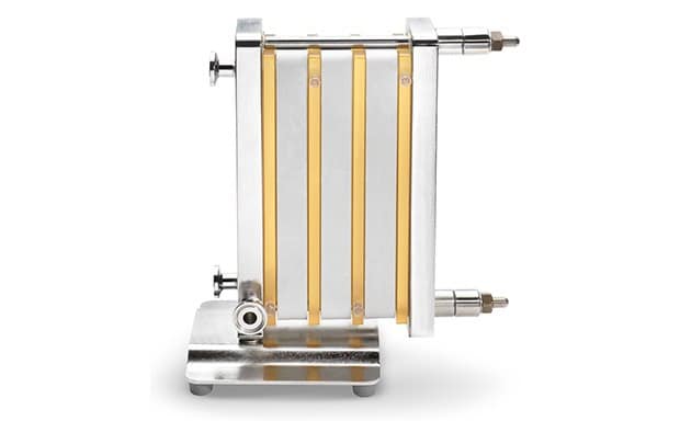 Pellicon® Single-Pass TFF a tangential flow filtration device characterized by multiple yellowish tubes aligned vertically and parallel, connected to a metallic frame, with four rods securing the structure, and a robust metallic base for stability during operation.