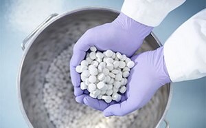 Newly produced tablets held in the gloved hands of a pharmaceutical worker