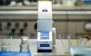 实验室环境中的PennPhD光反应器，采用白色和灰色设计，带数字控制，背景为柔焦的实验室设备。