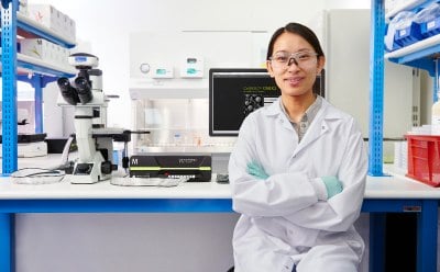 科学家站在 Luminex® 仪器旁，手持一盒 MILLIPLEX® 多路复用生物标记检测试剂，背景是工作台上的 SMCxPRO® 超灵敏免疫测定仪器