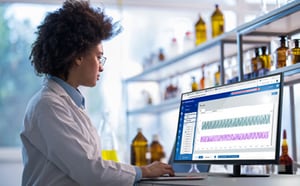 Female scientist in lab coat using laptop using control software to automate, monitor, and control a bioprocess unit operation