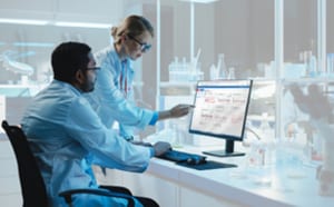 实验室内两名科研人员正在电脑显示器上查看可视化的生物工艺数据