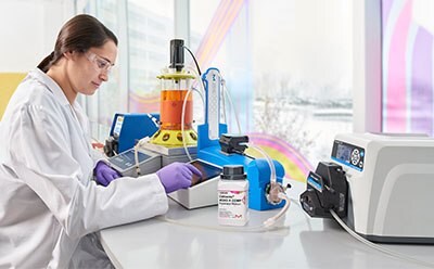 一位科学家坐在窗边的白色实验台前，正在操作一个生物反应器。