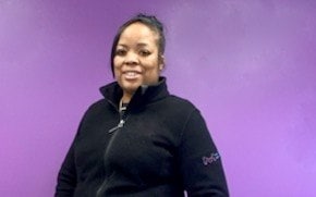 Chevon Adams Chevon Adams穿着黑色羊毛衫,站在一面紫色的墙壁前。