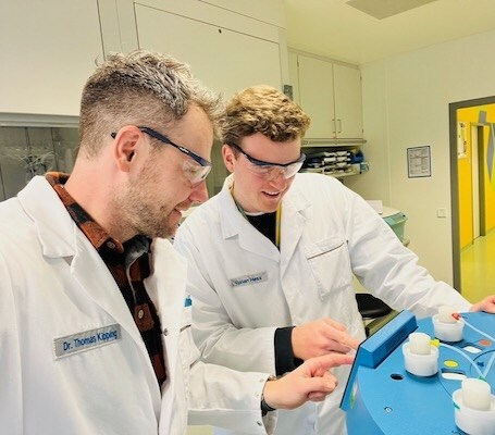 Thomas Kipping and Florian Hess Thomas Kipping和Florian Hess一起操作仪器。他们都戴着护目镜盯着控制面板。