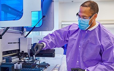 Male lab technician with protection clothes doing some tests by using a machine.